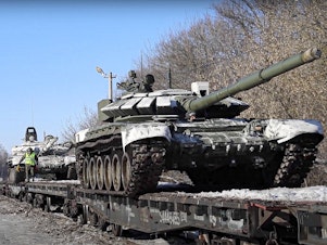 caption: In this photo taken from video provided by the Russian Defense Ministry Press Service on Wednesday, Russian army tanks are loaded onto railway platforms to move back to their permanent base after drills in Russia.