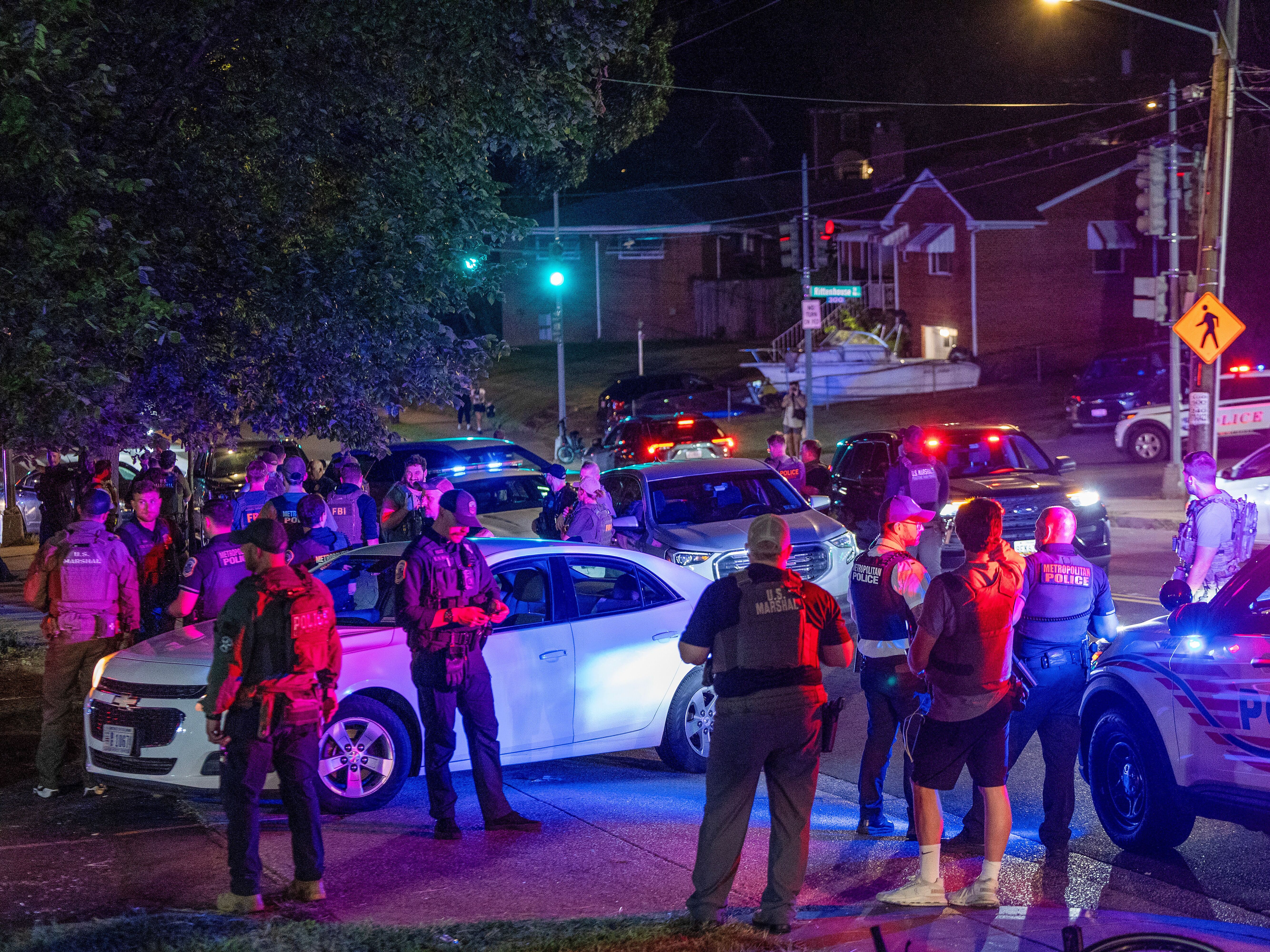 caption: More than a dozen law enforcement officers, including Washington, D.C., Metro police, FBI, Homeland Security and Secret Service agents, make a felony traffic stop on Saturday. An increased presence of law enforcement has been seen throughout the nation's capital since President Trump announced plans to deploy federal officers and the U.S. National Guard.