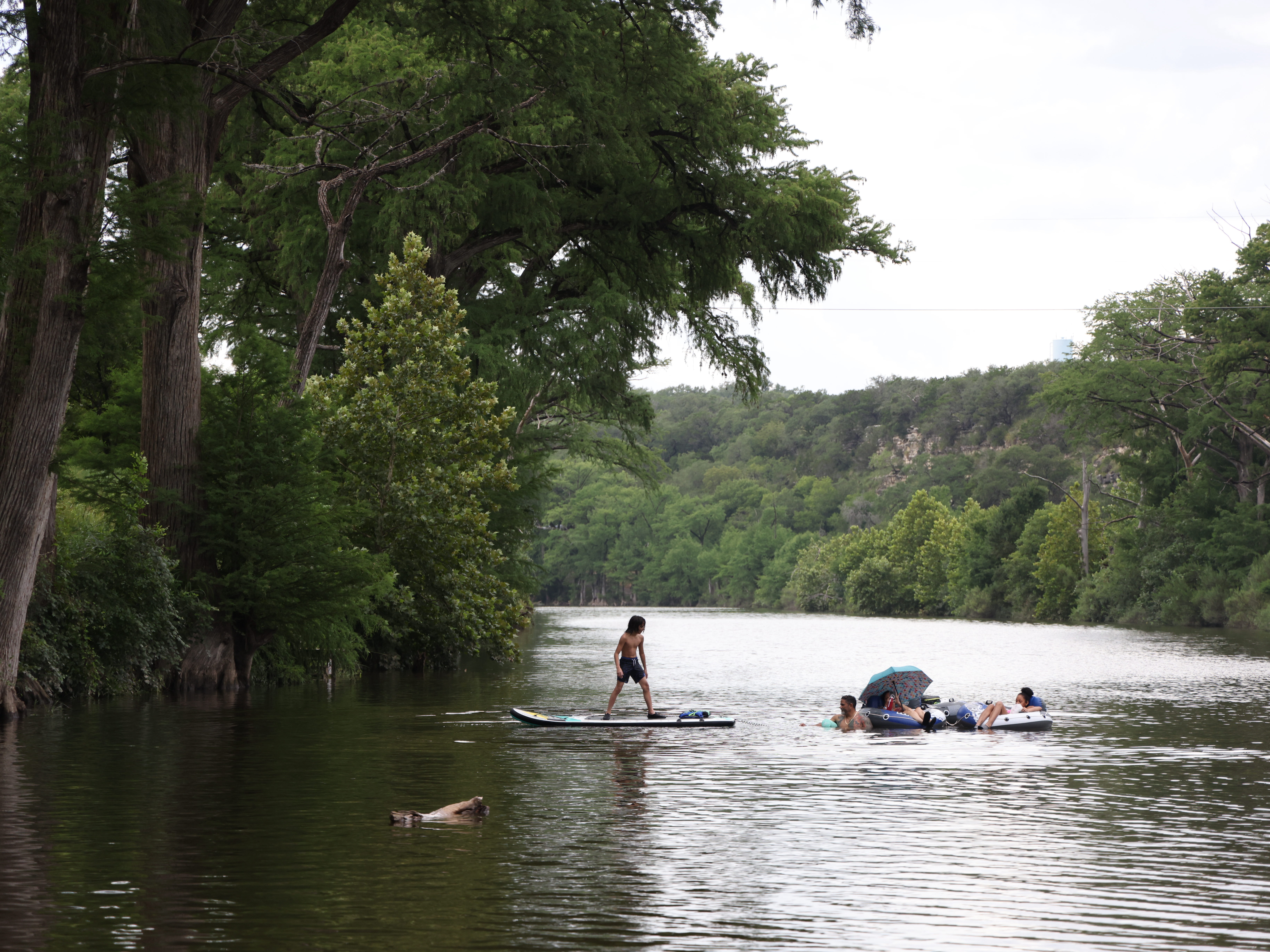 caption: People swim in the Blanco River by a low water crossing on River Road across from 7A Ranch in Wimberley, Texas, on July 9.
