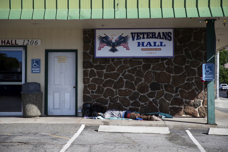 caption: A person sleeps outside of the Veteran’s Hall on Thursday, July 10, 2025, in Wenatchee.