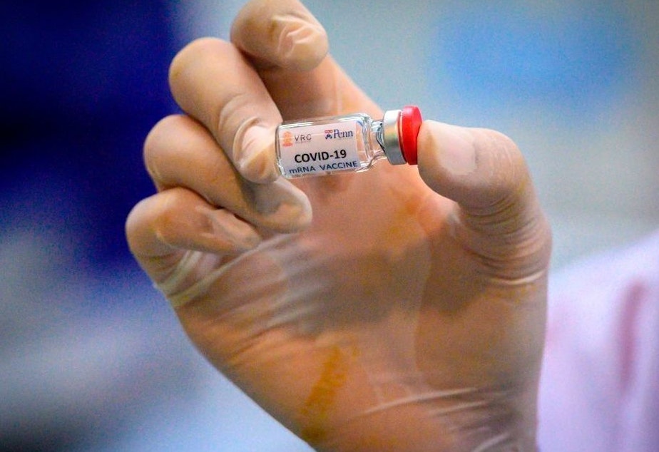 caption: A laboratory technician holds a dose of a COVID-19 vaccine candidate ready for a trial in May 2020.