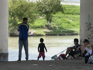 caption: Migrants waiting to be picked up by the U.S. Border Patrol under an international bridge in Eagle Pass, Texas, earlier this month.