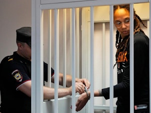 caption: A guard removes Brittney Griner's handcuffs ahead of a hearing at the Khimki Court outside Moscow on Wednesday.