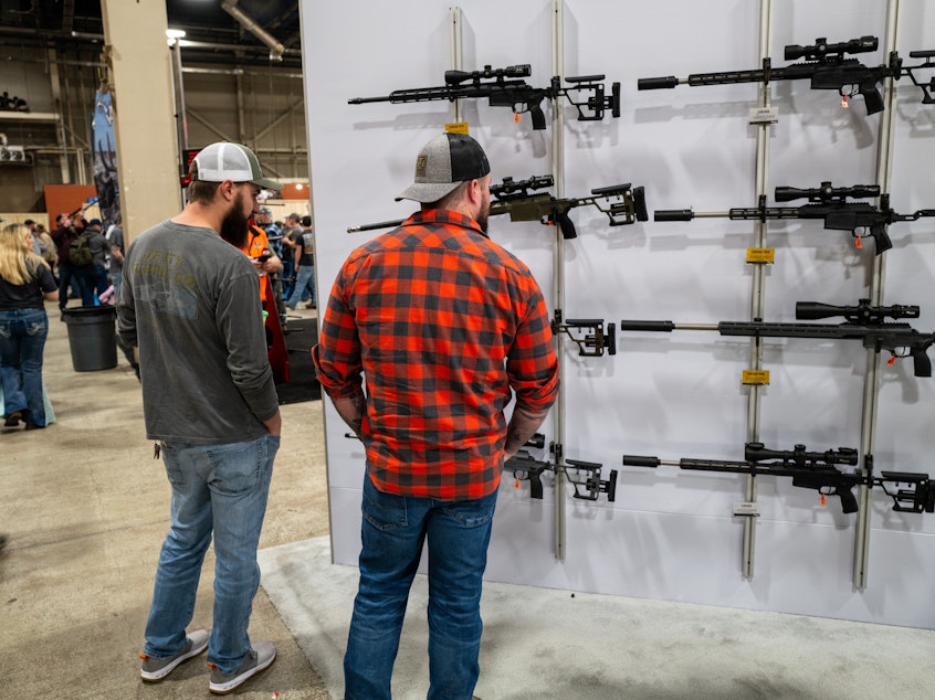 caption: People look at guns and ammunition at the Great American Outdoor Show on Feb. 9 in Harrisburg, Penn. Former President Donald Trump spoke at the event.