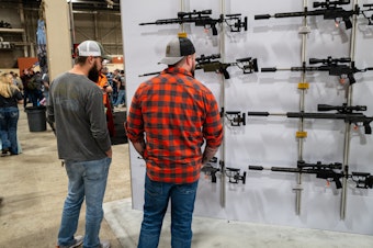 caption: People look at guns and ammunition at the Great American Outdoor Show on Feb. 9 in Harrisburg, Penn. Former President Donald Trump spoke at the event.