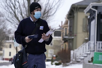 caption: Postal carrier Josiah Morse in Portland, Maine. The USPS is seeking a temporary delay from COVID-19 vaccine requirements.