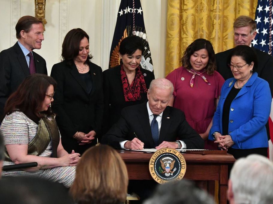 caption: President Biden signs into law the COVID-19 Hate Crimes Act on Thursday in the East Room of the White House.