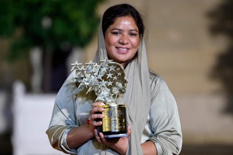caption: Pakistani teacher Riffat Arif, known as Sister Zeph, is the 2023 winner of the Varkey Foundation Global Teacher Prize. She holds a trophy presented at a dinner in her honor in Paris. She says she faced bad treatment from her teachers at school and dreamed of "a teacher who gives equal respect and love to children with no difference. I could not find that teacher, so I will be that teacher."