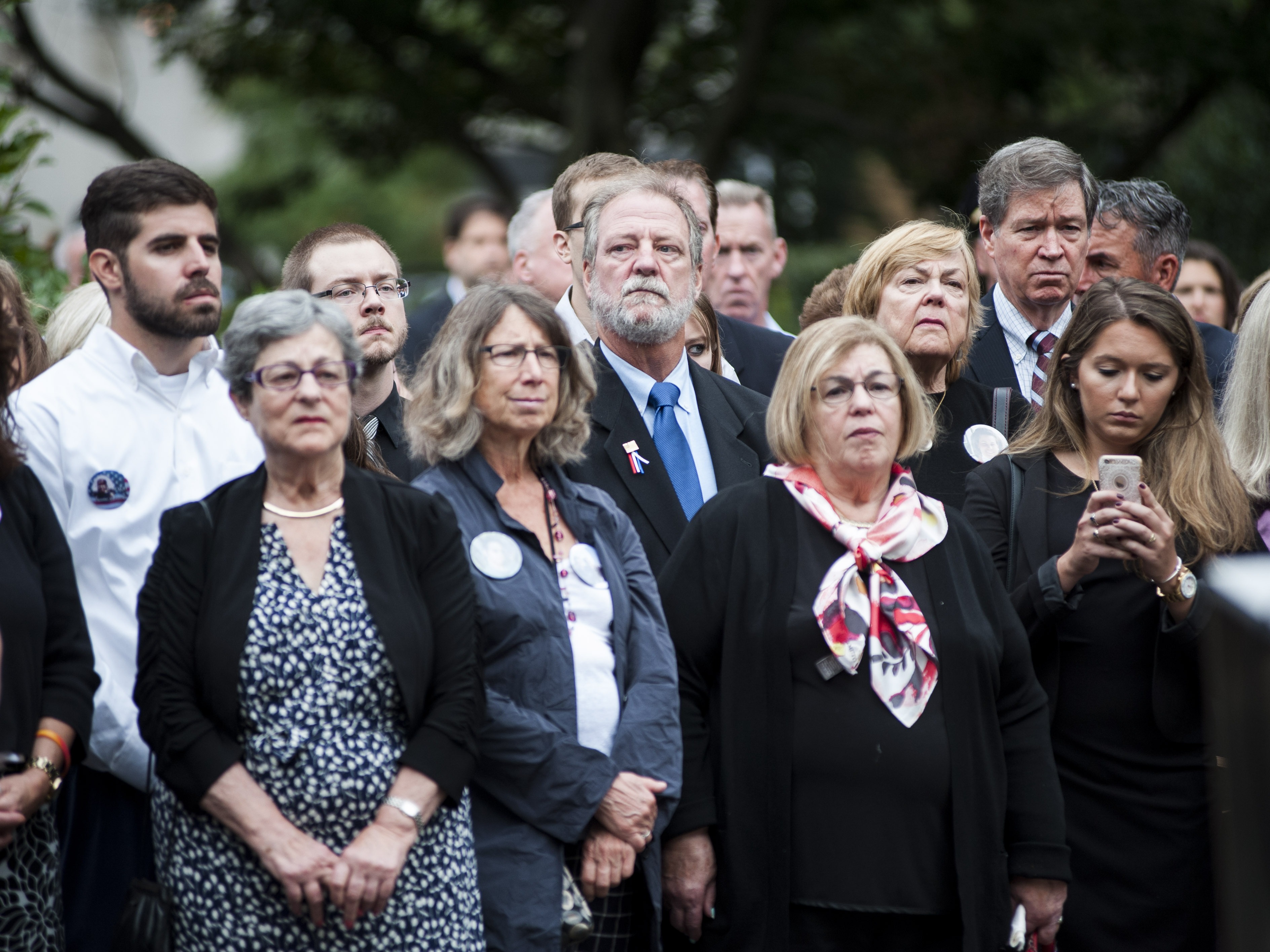 caption: Michael Keating, center in the second row, stands during the wreath laying at the 9/11 memorial at the Boston Public Garden. His mother, Barbara Ann Keating, was killed during the September 11th attacks in 2001. September 11, 2016.
