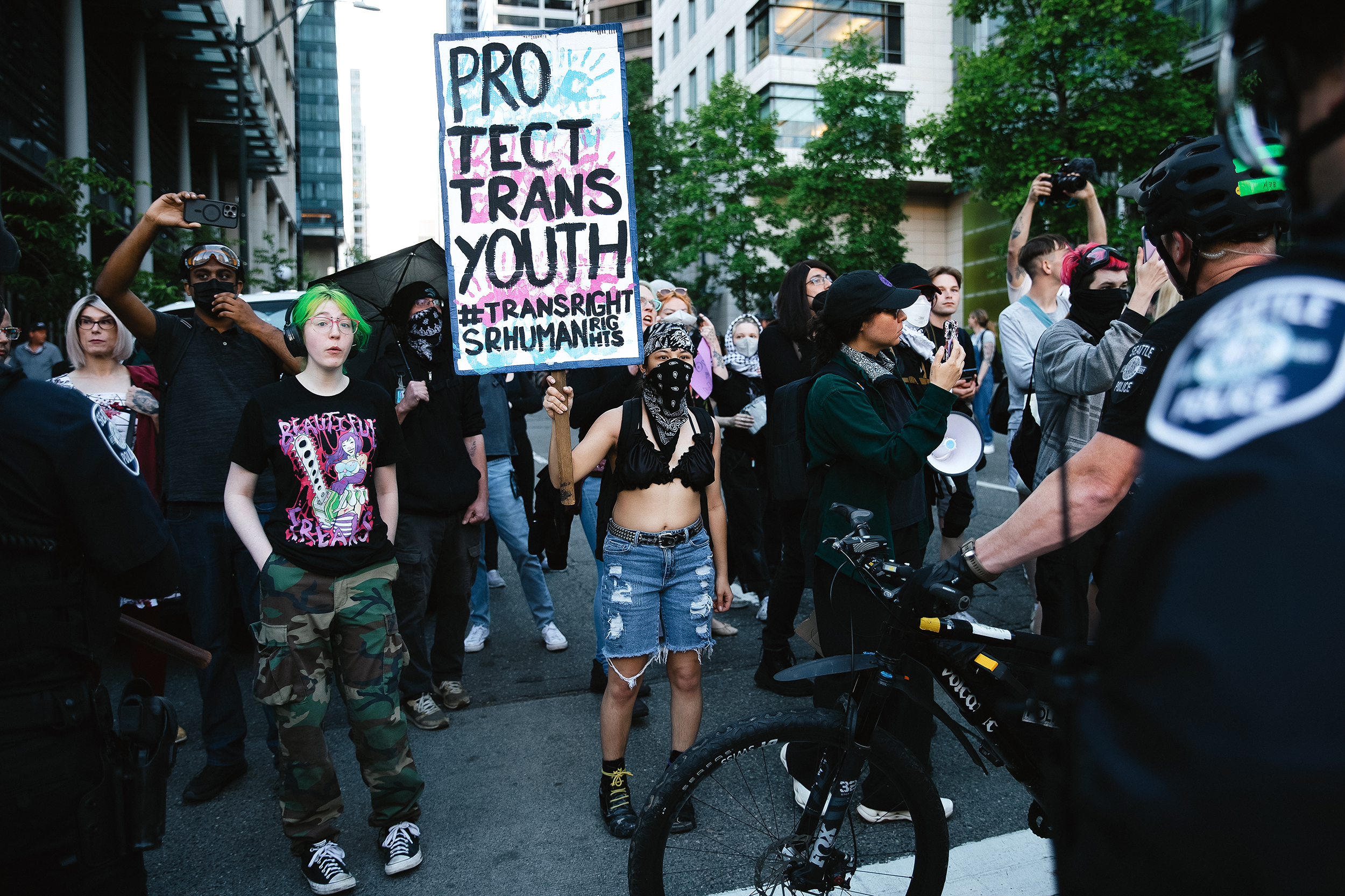 caption: Counter-protesters clash with Seattle police officers outside of the fundamentalist Christian group Mayday USA’s ‘Rattle in Seattle’ event, on Tuesday, May 27, 2025, at Seattle City Hall. The group advocates against trans rights. 
