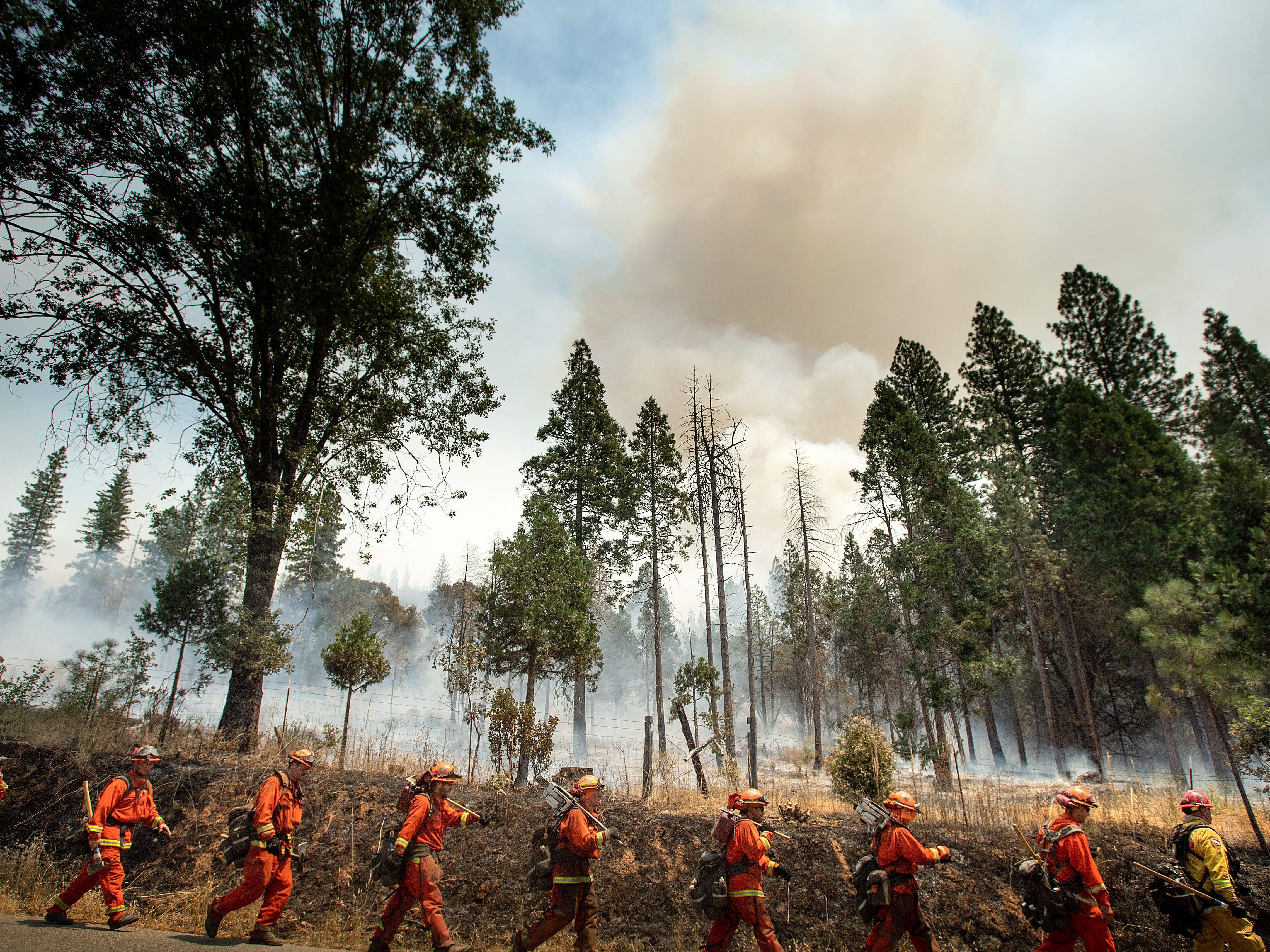 caption: Inmate firefighters battle a California wildfire in July. Qualified inmates can volunteer to be trained in firefighting; in exchange, they are paid $2 a day and an extra $1 per hour when fighting fires. The inmate firefighters also receive sentence reductions.