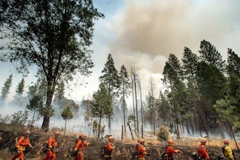caption: Inmate firefighters battle a California wildfire in July. Qualified inmates can volunteer to be trained in firefighting; in exchange, they are paid $2 a day and an extra $1 per hour when fighting fires. The inmate firefighters also receive sentence reductions.