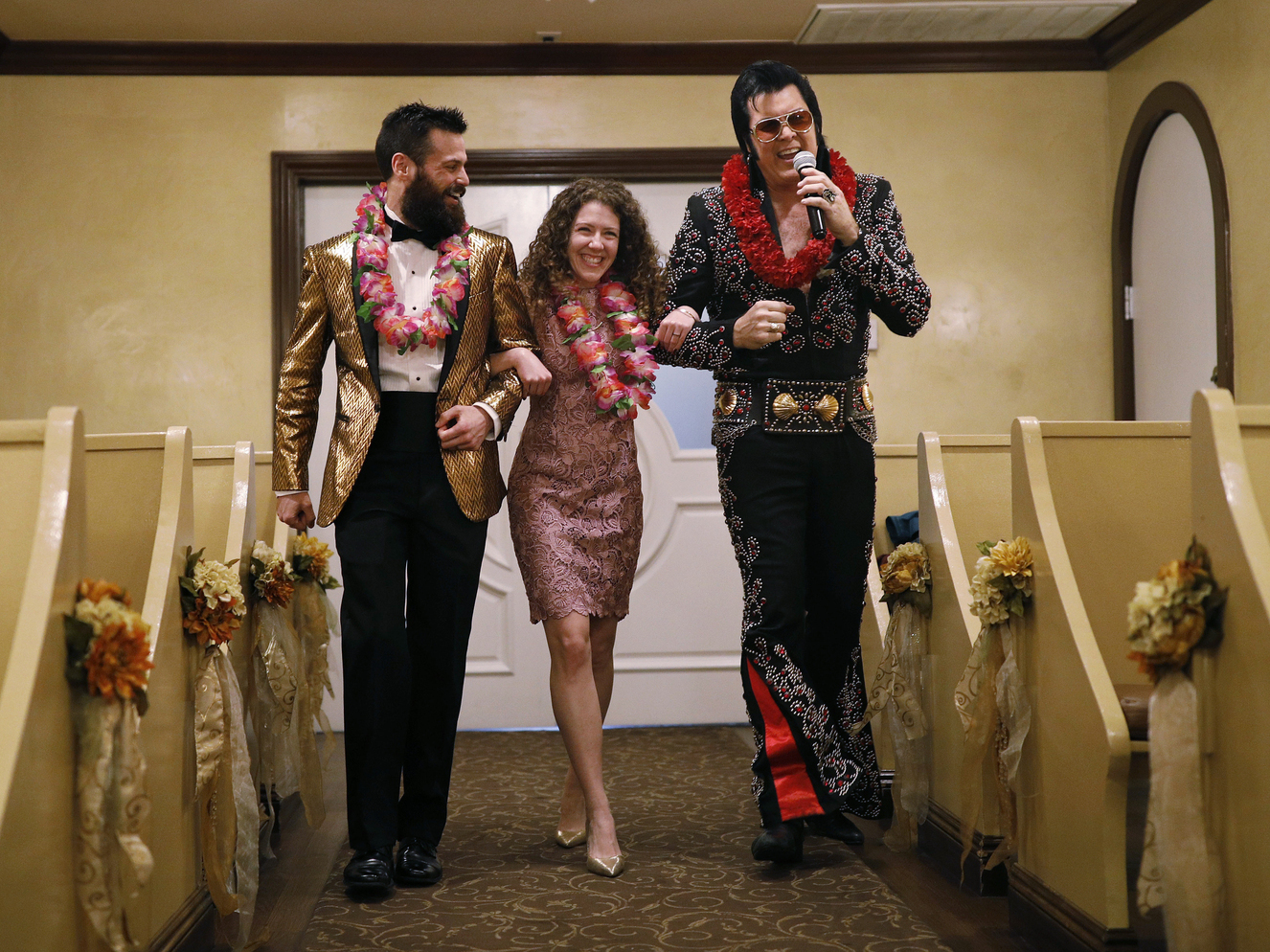 caption: Elvis impersonator Brendan Paul (right) walks down the aisle during a wedding ceremony for Katie Salvatore and Eric Wheeler at the Graceland Wedding Chapel in Las Vegas.