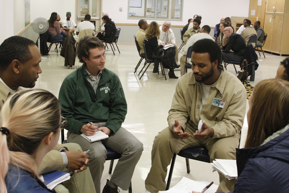caption: Teacher-in-training Mitch Ahmann (L) and others listen to Tony (R), a member of the Black Prisoners Caucus, at Monroe Correctional Complex on March 1, 2019.