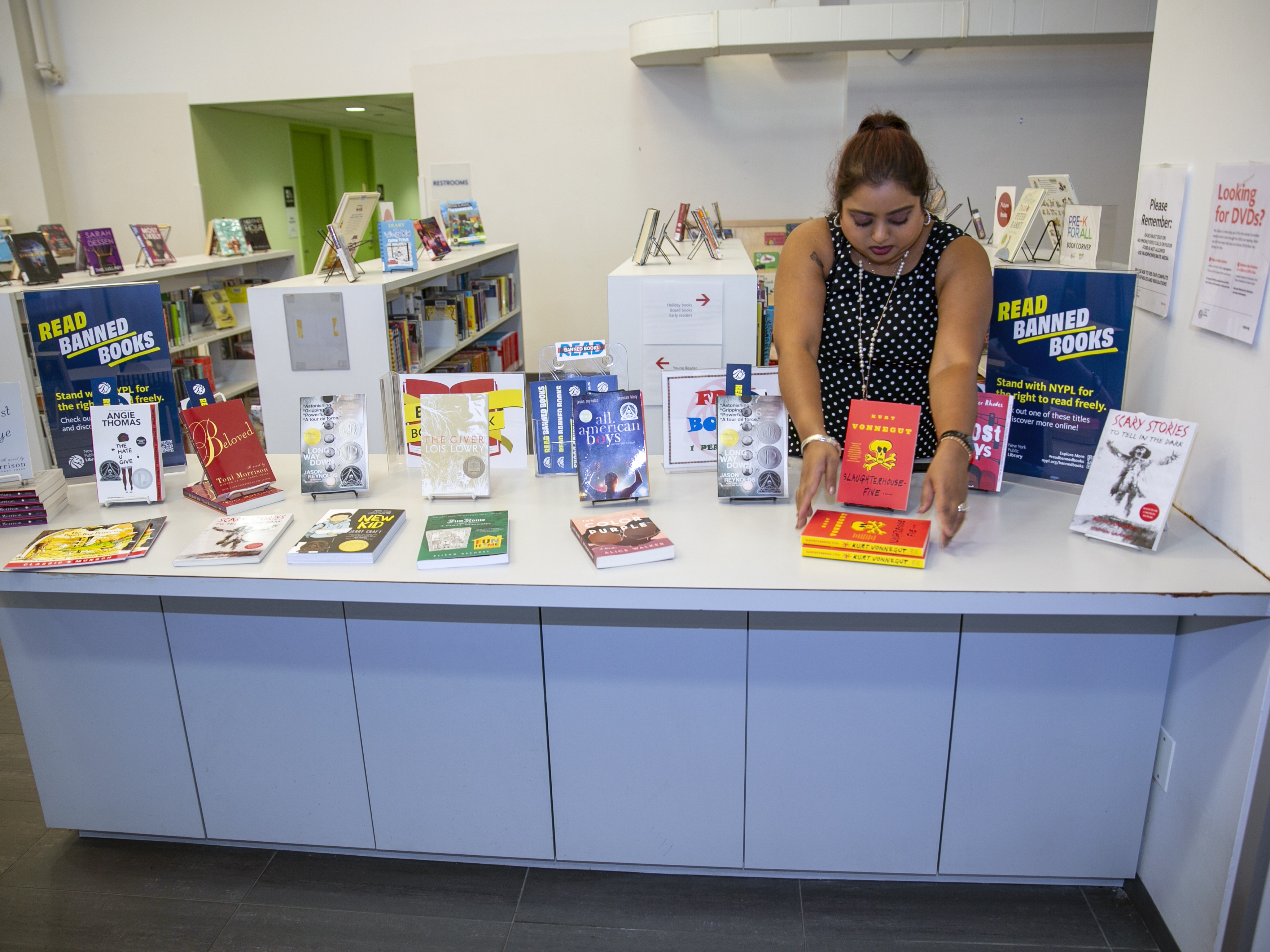 caption: Librarian Sabrina Jesram arranges a display of books during Banned Books Week at a public library branch in New York City on Sept. 23, 2022. 