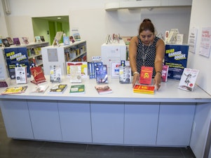 caption: Librarian Sabrina Jesram arranges a display of books during Banned Books Week at a public library branch in New York City on Sept. 23, 2022. 
