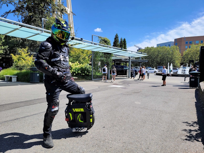 caption: Jim Chow stands with his electric unicycle in front of the Seattle Space Needle on August 8, 2022.