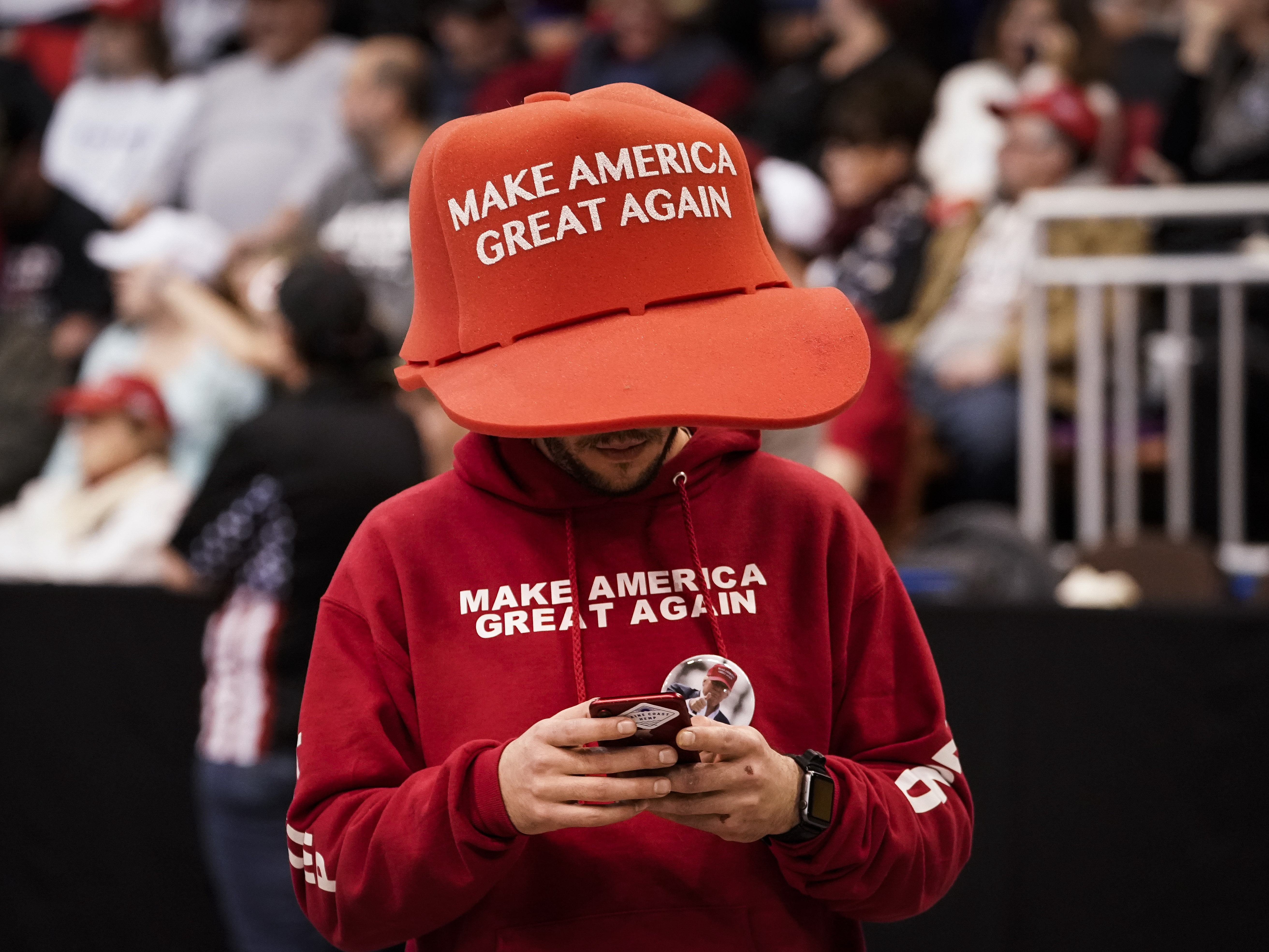 caption: A supporter of President Trump wears an oversize "Make America Great Again Hat" at a rally at Southern New Hampshire University Arena on Feb. 10, 2020, in Manchester, N.H. Trump narrowly won young men last fall, a 12-point shift from four years earlier when Biden won the group by 11 percentage points.