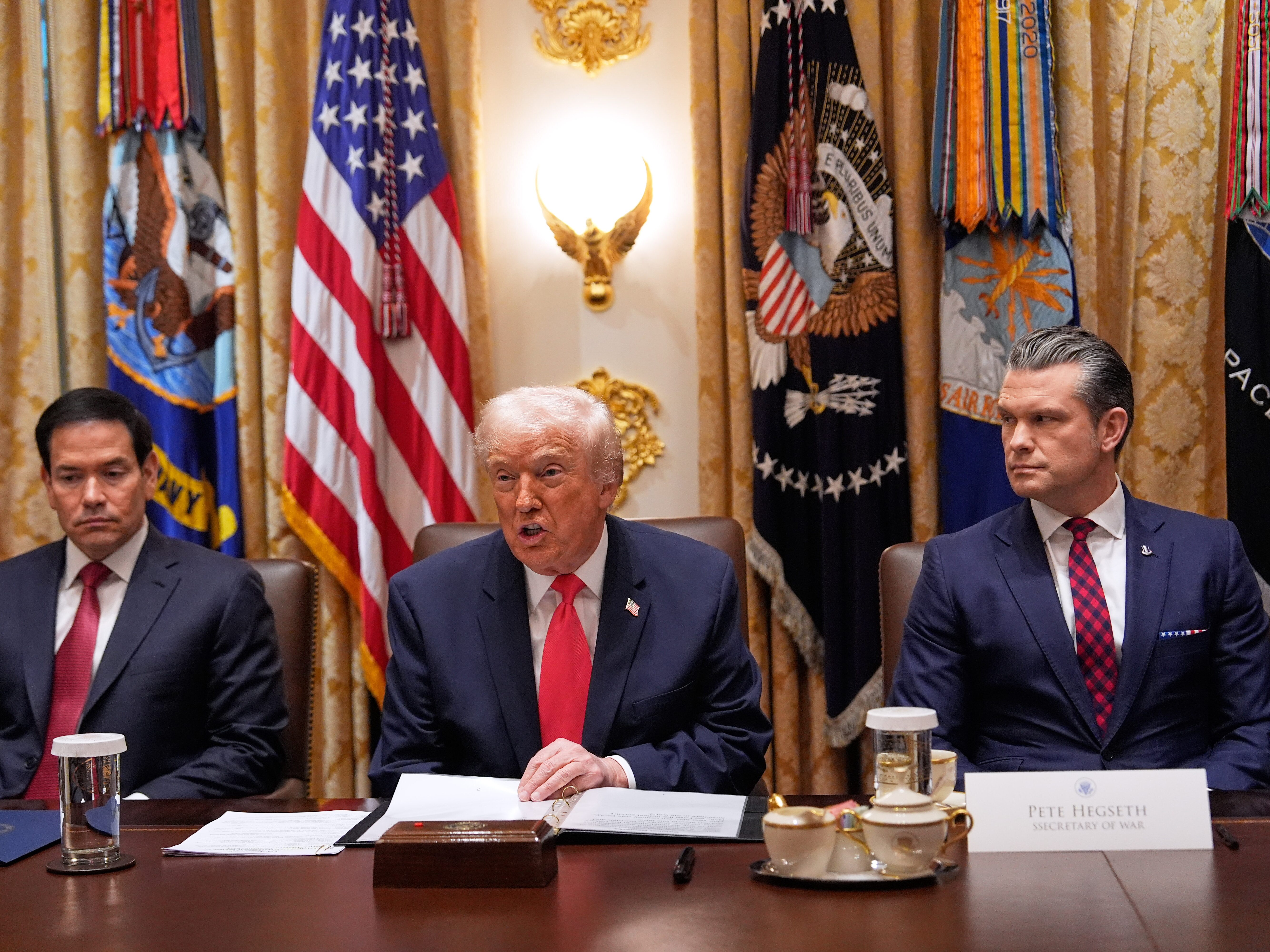 caption: President Trump speaks during a Cabinet meeting at the White House, Tuesday, as Secretary of State Marco Rubio (left) and Defense Secretary Pete Hegseth look on.