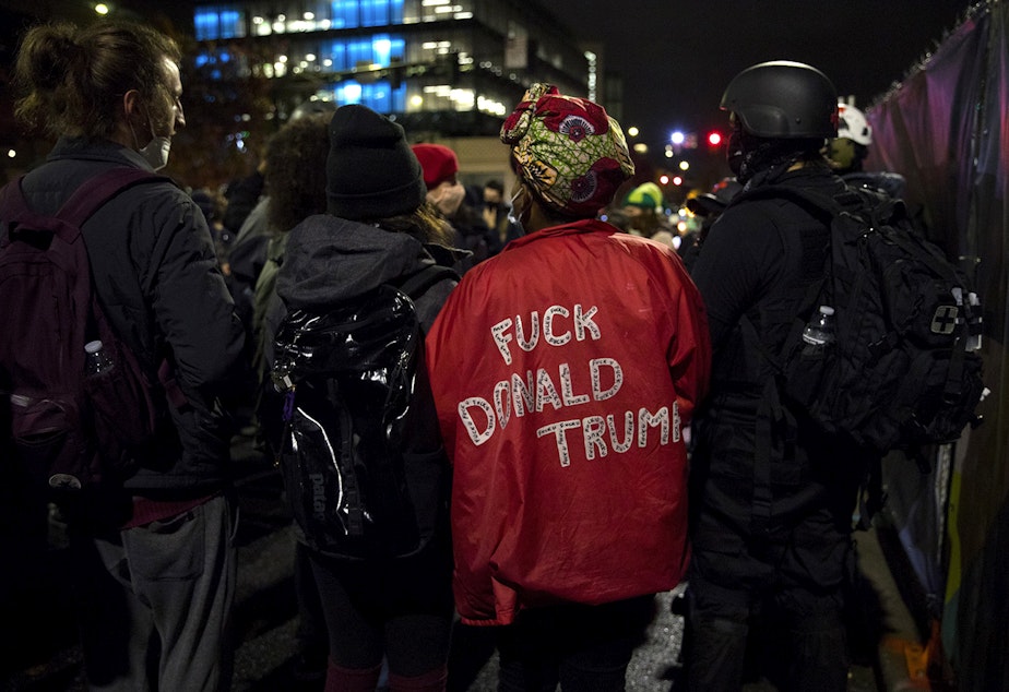 caption: Protester Angelica C. wears a jacket that reads 'Fuck Donald Trump,' while marching through the South Lake Union neighborhood with multiple groups protesting for racial justice and against police brutality on the night of the 2020 presidential election, on Tuesday, November 3, 2020, in Seattle.