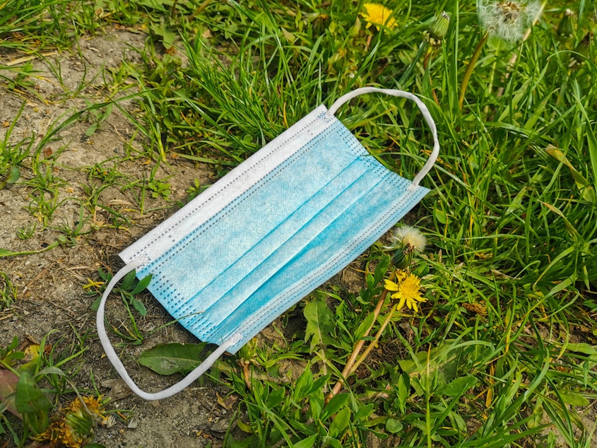 caption: A face mask languishes in the grass in Krakow, Poland. With the state of emergency over, some people are relishing freedom from masks while others believe masking up is still a wise preventive measure.
