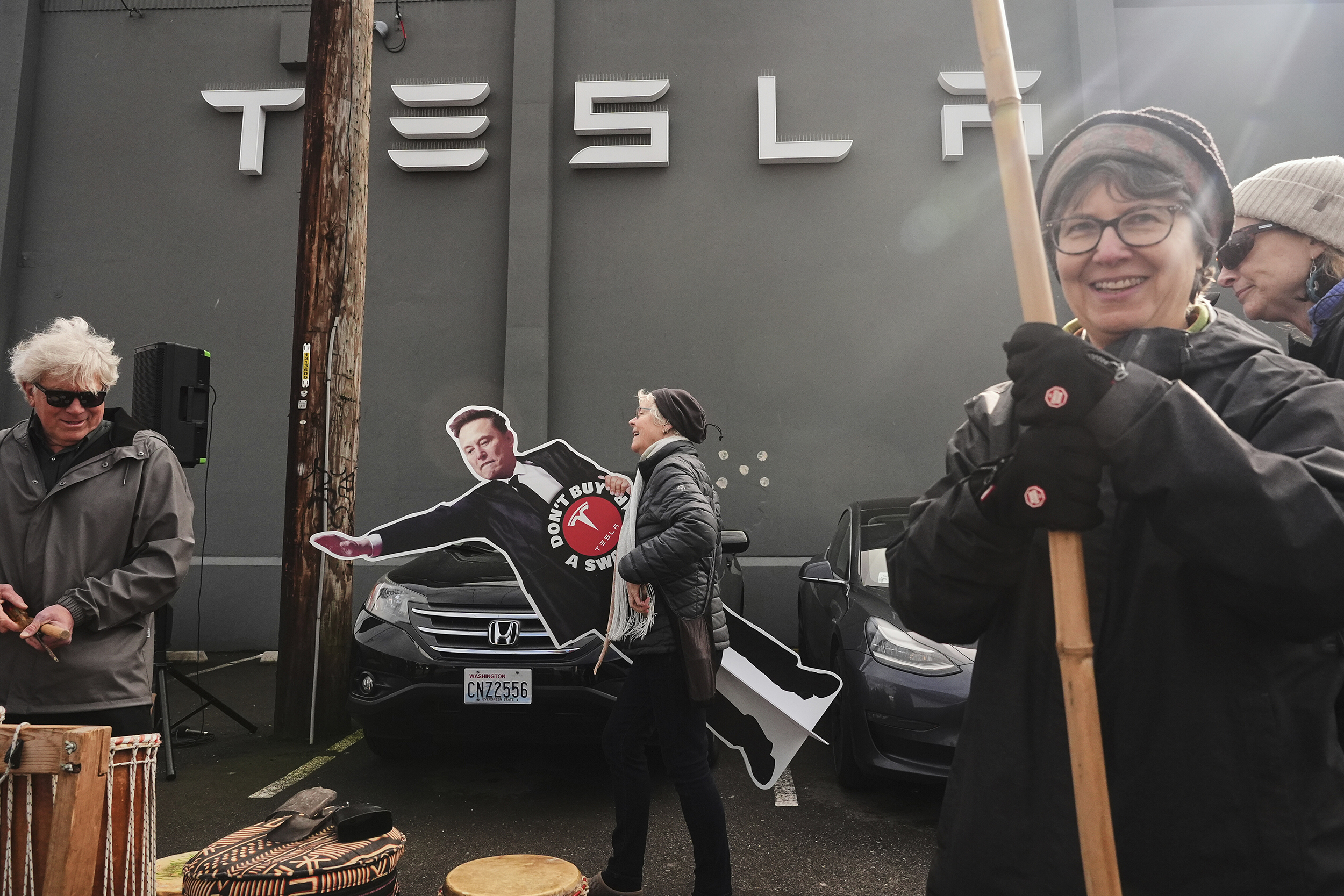 caption: A protester carries a cutout of Elon Musk during a protest against Tesla and Elon Musk Saturday, March 29, 2025, outside a service center in Seattle. 