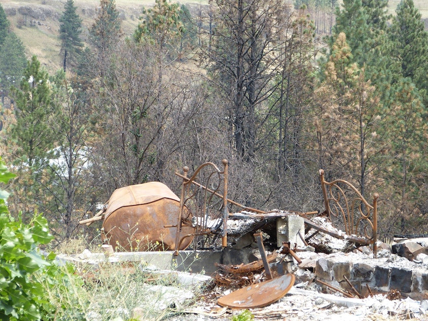 A pile of burned debris, ash, rubble including a metal bed frame