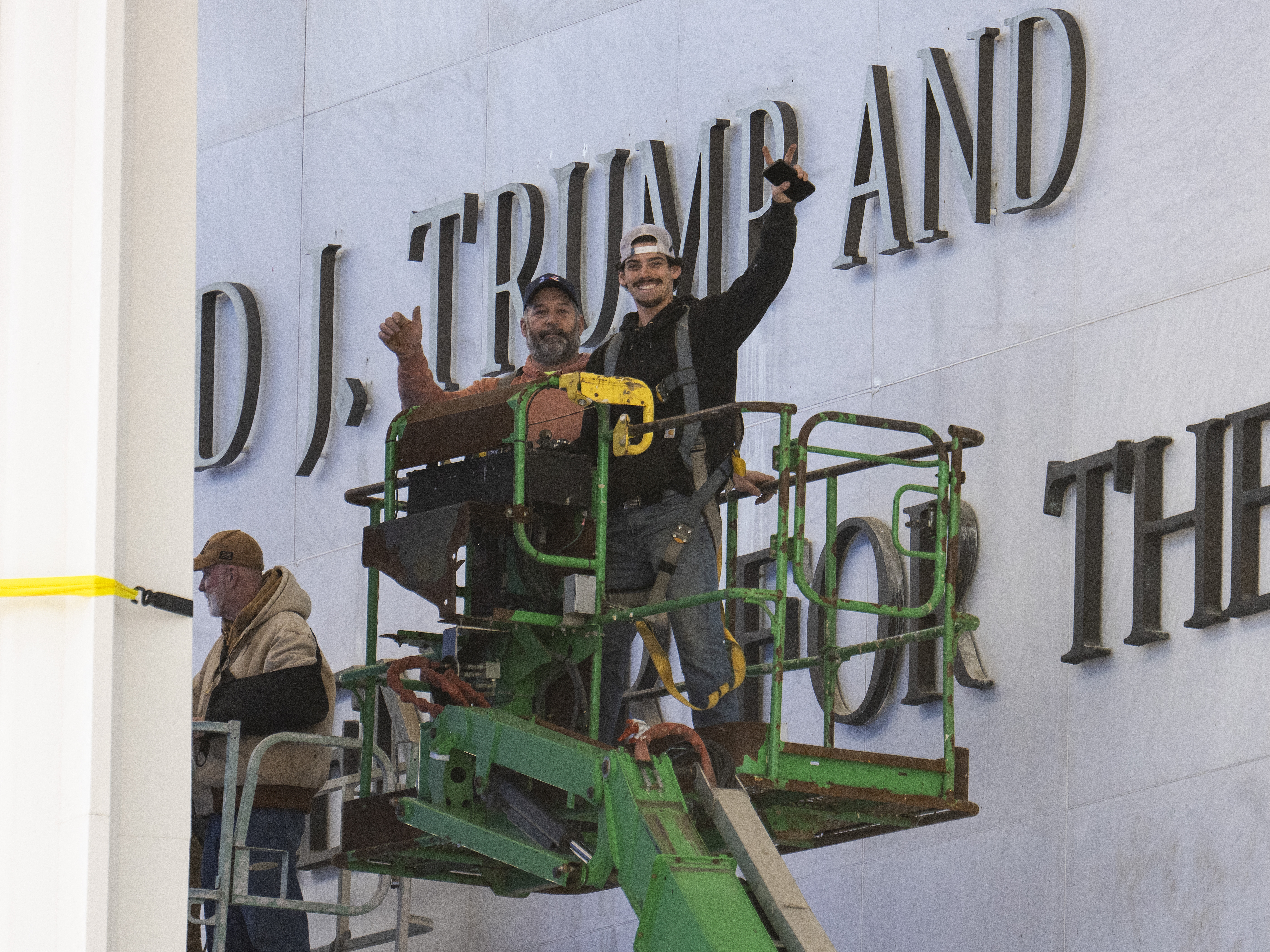 caption: Workers react to the media after updating signage outside the Kennedy Center on Dec. 19, 2025, in Washington, D.C.