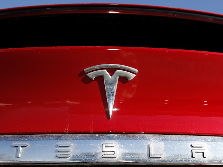 caption: The Tesla company logo is shown in Littleton, Colo., in 2020. Tesla is recalling nearly all of the vehicles it has sold in the U.S. because some warning lights on the instrument panel are too small.