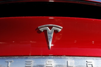 caption: The Tesla company logo is shown in Littleton, Colo., in 2020. Tesla is recalling nearly all of the vehicles it has sold in the U.S. because some warning lights on the instrument panel are too small.