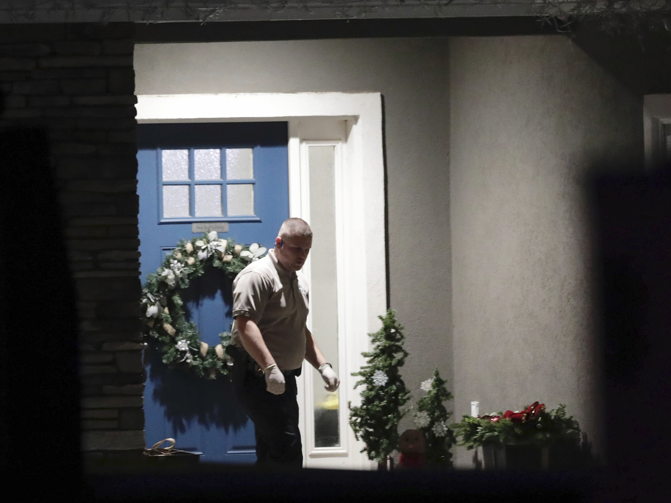 caption: A law enforcement official stands near the front door of the Enoch, Utah, home where eight family members were found dead from gunshot wounds, Wednesday, Jan. 4, 2023.