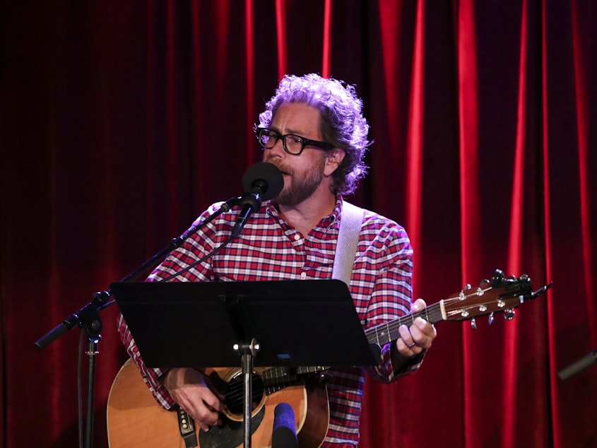 caption: <em>Ask Me Another</em> house musician Jonathan Coulton leads a music parody game at the Bell House in Brooklyn, New York.
