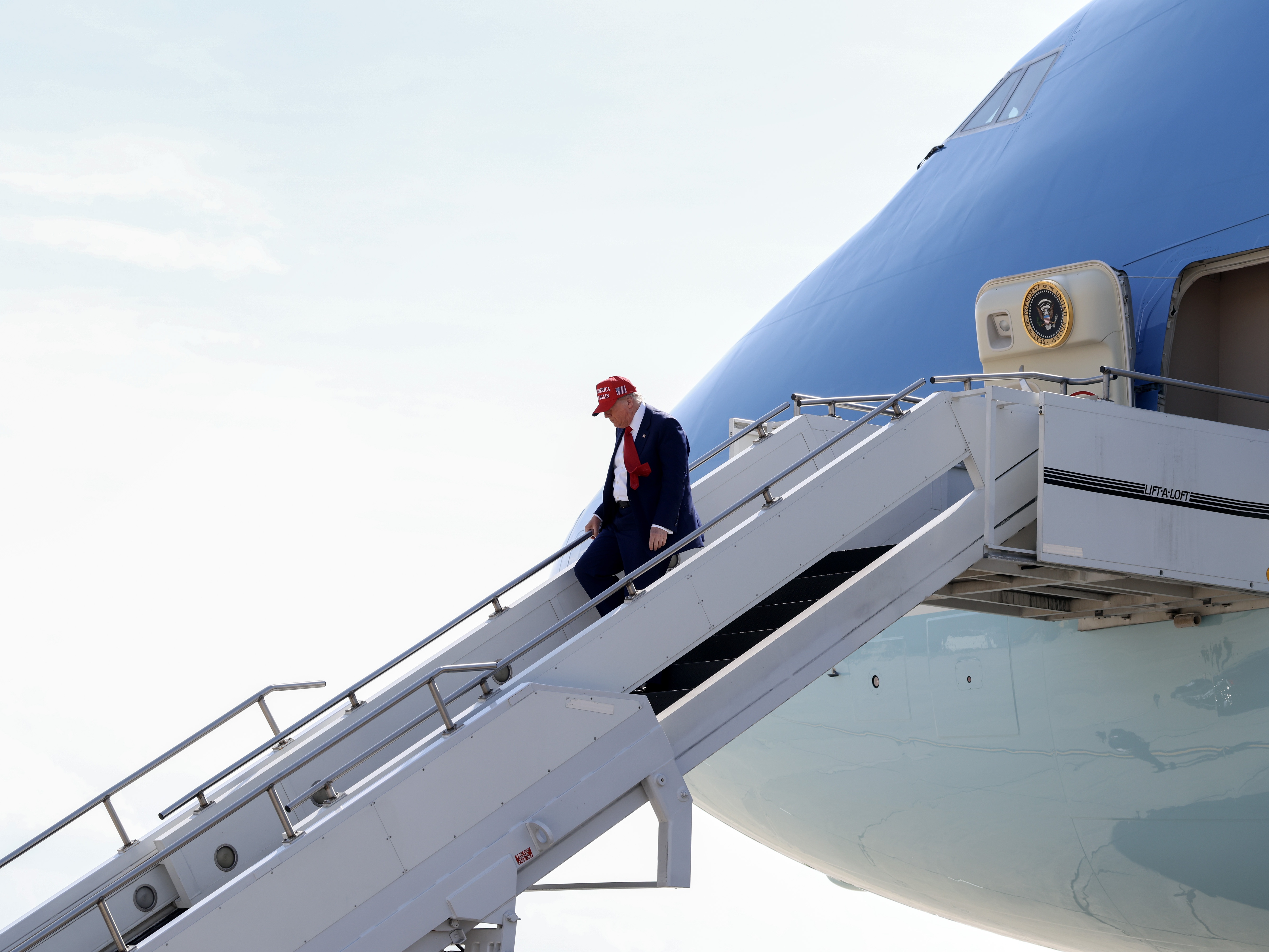 caption: President Trump walks off Air Force One on April 29 at Selfridge Air National Guard Base, Michigan. Qatar has offered to replace Air Force One with a luxury Boeing 747 jet.