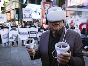 caption: A person standing near Times Square in New York City wears a virtual reality headset screening an immersive experience of the conditions at Venezuela's El Helicoide prison, on Sept. 19, 2023. Protesters gathered to demand the release of political prisoners and the closure of the detention center over allegations of torture.