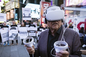 caption: A person standing near Times Square in New York City wears a virtual reality headset screening an immersive experience of the conditions at Venezuela's El Helicoide prison, on Sept. 19, 2023. Protesters gathered to demand the release of political prisoners and the closure of the detention center over allegations of torture.