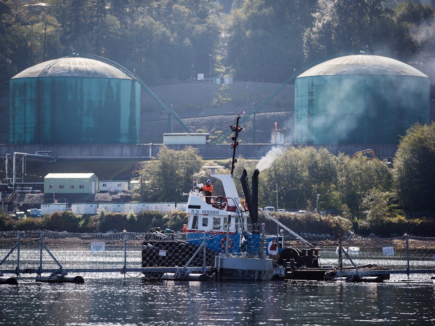 caption: A tugboat operator secures a floating razor wire security fence during an emergency response exercise at the Kinder Morgan Inc. Westridge Marine Terminal in Burnaby, British Columbia, Canada, last September. A new expansion of the Trans Mountain pipeline would significantly expand tanker traffic in the region.