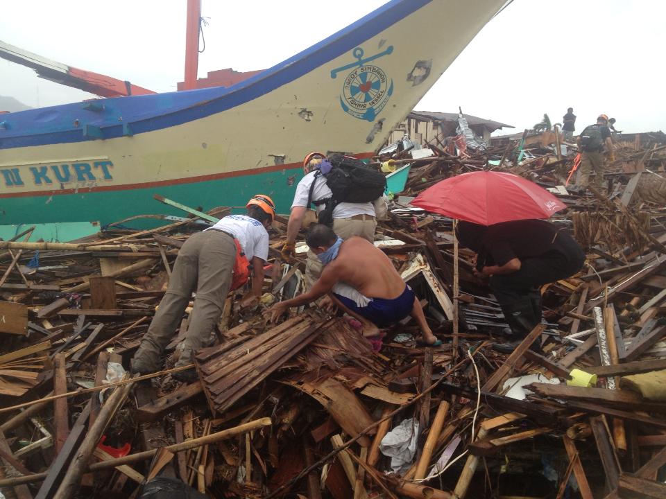 caption: Relief workers comb through wreckage of Typhoon Haiyan