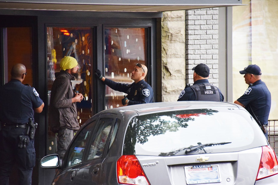 caption: Seattle Police Officer Louis Chan, center, talks with a man in Ballard about his erratic and threatening behavior. Several police units responded to the scene to assist.