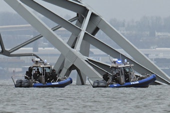 caption: Police recovery crews work near the collapsed Francis Scott Key Bridge after it was struck by the container ship Dali in Baltimore, Maryland.   Eight members of a construction crew repairing potholes were on the bridge when the structure fell into the Patapsco River at around 1:30 am on March 26.