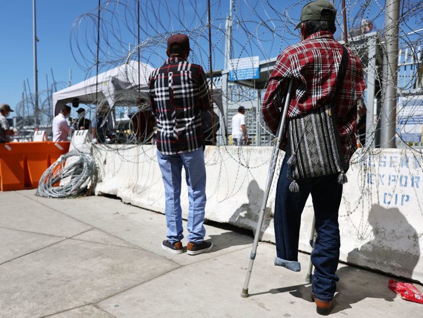 caption: An asylum seeker waits outside the San Ysidro Port of Entry in Tijuana, Mexico. The Biden administration is bracing for a possible surge in migration if it lifts the pandemic border restrictions known as Title 42.