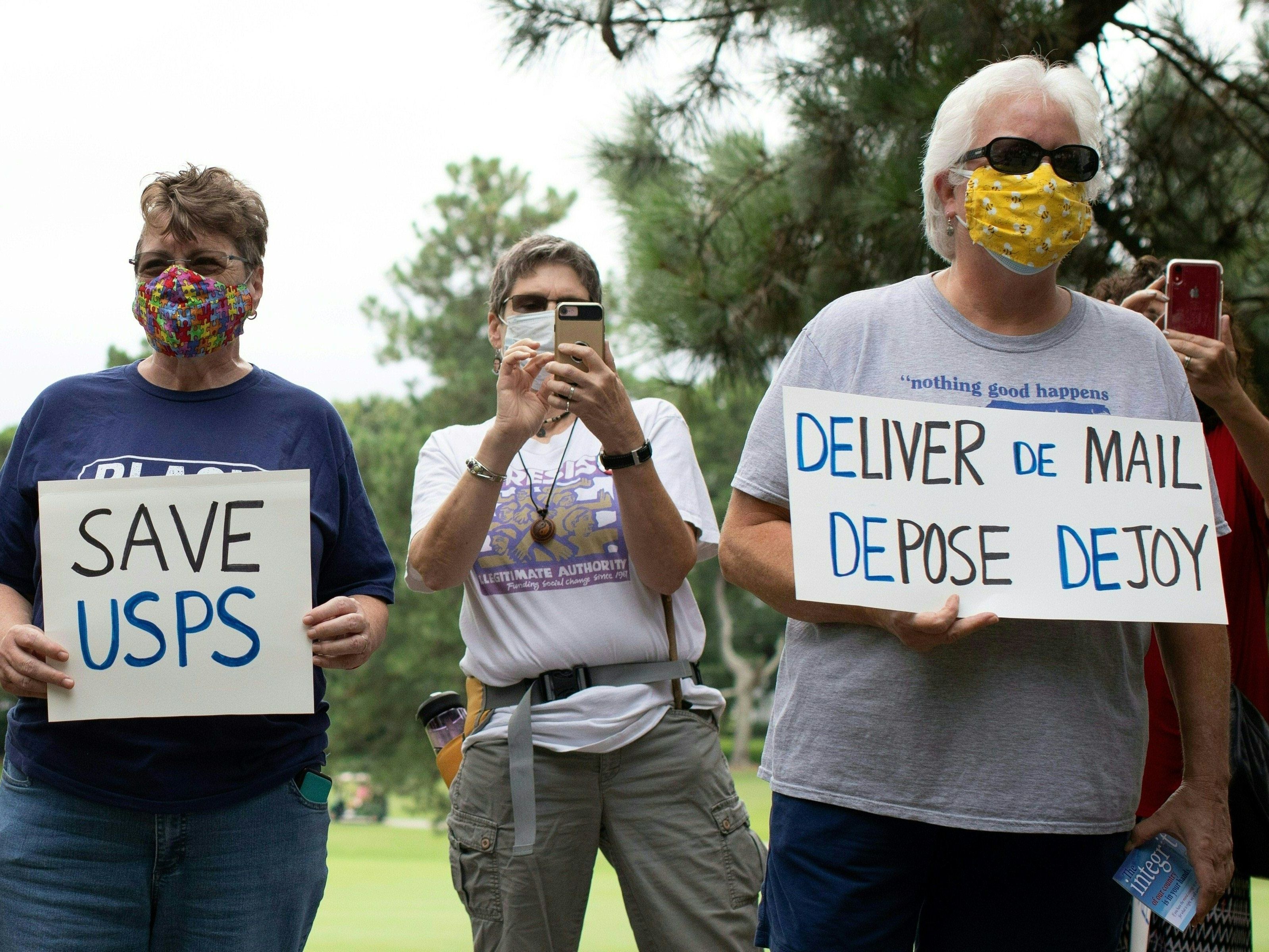caption: A group of protesters demonstrate in front of Postmaster General Louis DeJoy's home in Greensboro, N.C., on Sunday.