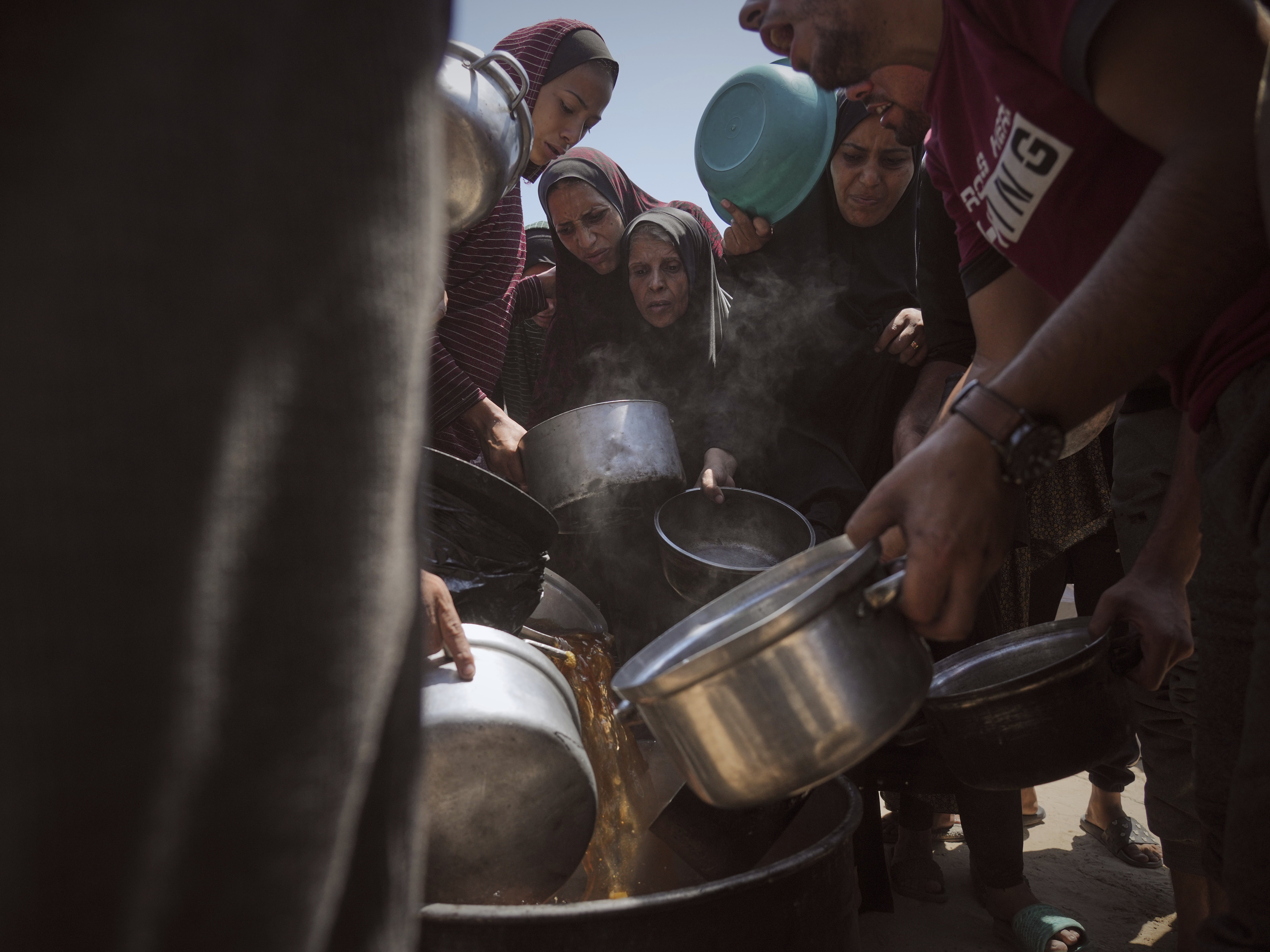 caption: Displaced Palestinians receive donated food at a community kitchen in Gaza City, northern Gaza Strip on Tuesday.