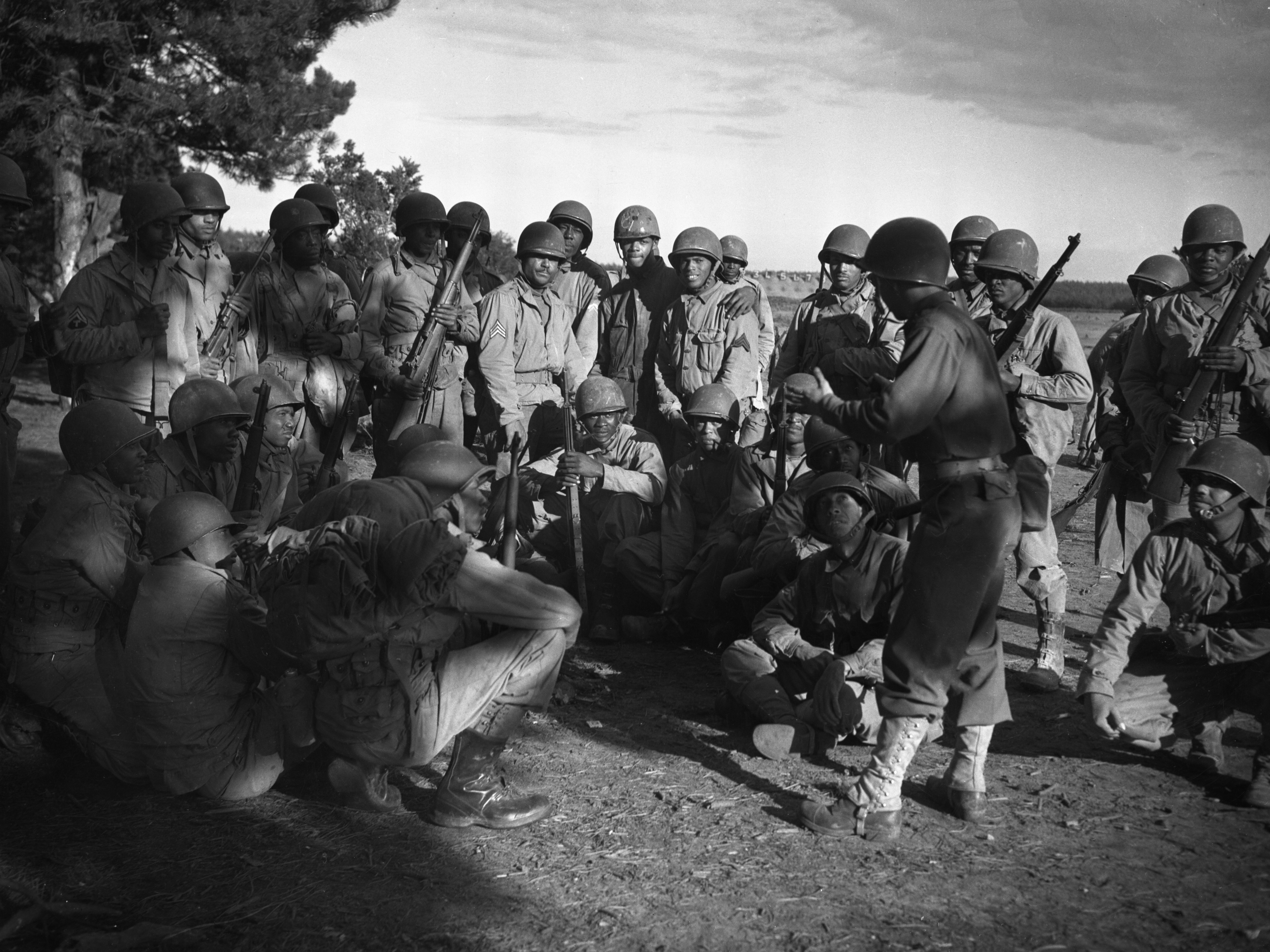 caption: Lt. Frank J. Crawford of Detroit, Michigan, as the Regimental plans and training officer, is giving his men instructions in combat maneuvers.