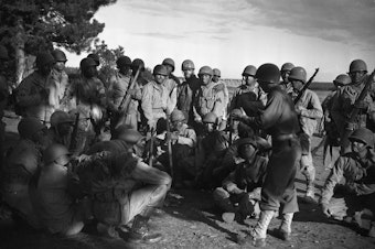 caption: Lt. Frank J. Crawford of Detroit, Michigan, as the Regimental plans and training officer, is giving his men instructions in combat maneuvers.