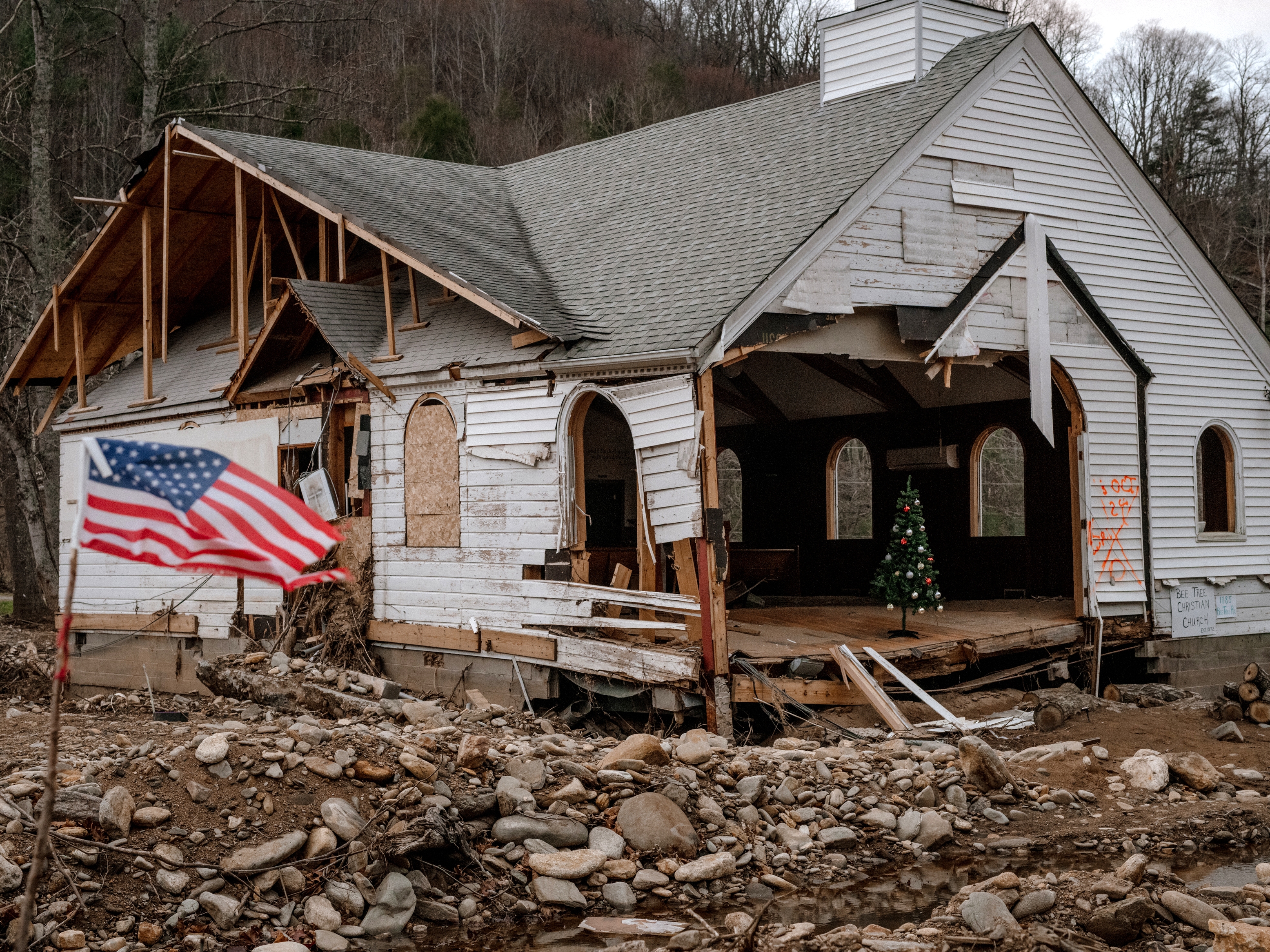 caption: The Bee Tree Christian Church in Swannanoa, North Carolina, is next to the Paez family's home. Both the Paez home and the church were inundated by Hurricane Helene's flood waters in late September. Nearly three months later, the area is still devastated.