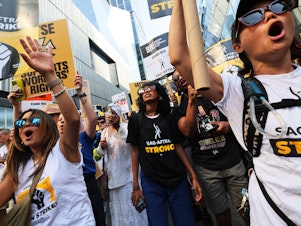 caption: People hold signs as members of SAG-AFTRA and Writers Guild of America East walk a picket line outside of the HBO/Amazon offices during the National Union Solidarity Day in New York City on Aug. 22, 2023. Labor unions have notched some big victories this year but organized labor still faces an uncertain future.
