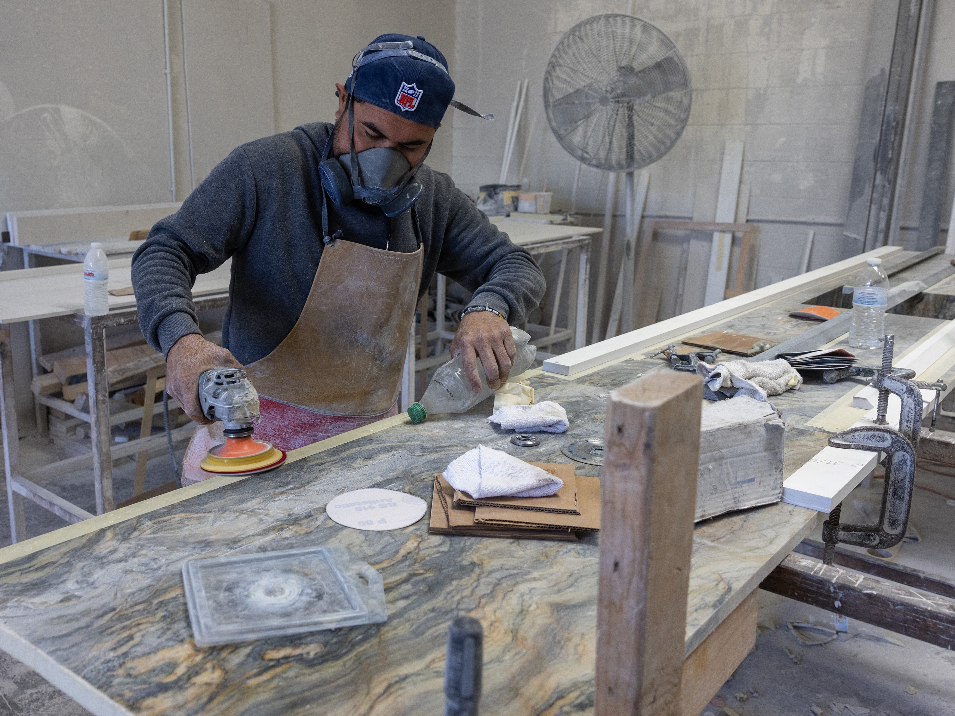 caption: A stone countertop fabricator wears a mask to help protect against airborne particles which can contribute to silicosis at a shop in Sun Valley, Calif.