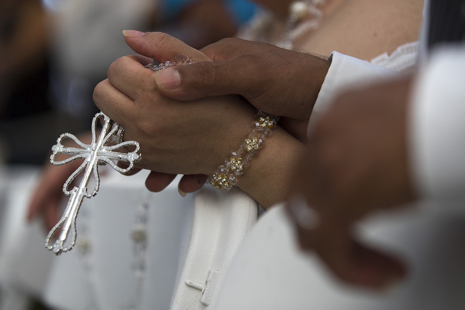 caption: Ana Dely Morales and Ramon Sanchez Cordova hold a lasso de boda together during a mass wedding ceremony where they were married along with 22 other couples on Sunday, June 2, 2019, at Our Lady of the Desert Church in Mattawa. 