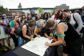 caption: Mud Bay workers sign a 'declaration' of worker ownership during a company meeting on Thursday, Aug. 20.