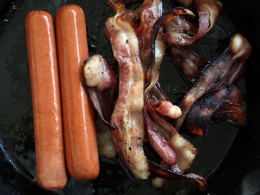 caption: Processed meats, including hot dogs and bacon, cook in a frying pan. A new study of 80,000 people finds that those who ate the most red meat — especially processed meats such as bacon and hot dogs — had a higher risk of premature death compared with those who cut back.